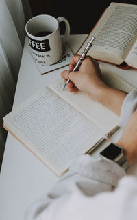 High angle view of woman writing in book on table