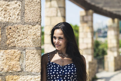 Beautiful smiling woman standing by column