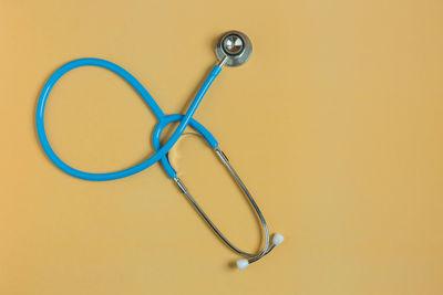 High angle view of stethoscope over beige background