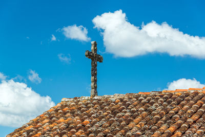 Low angle view of cross over roof tiles against sky