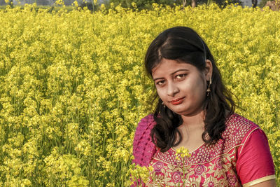 Portrait of woman with yellow flowers in field