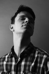 Young man with eyes closed against gray background