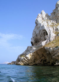 Scenic view of sea and rocks against blue sky