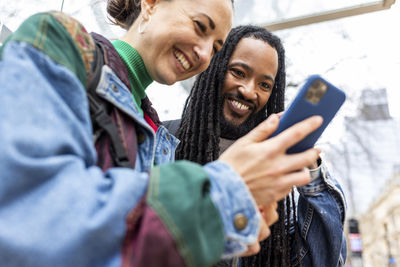 Smiling multiracial couple using smart phone