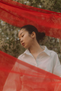 Portrait of young woman wearing hijab while standing against curtain