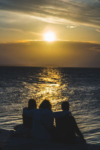Rear view of couple against sea during sunset