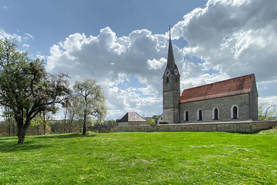 Scenic spring view meadow and church against sky,  hohendilching, community of valley, bavaria 