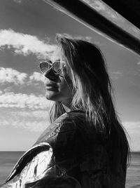 Portrait of young woman with sunglasses against sky