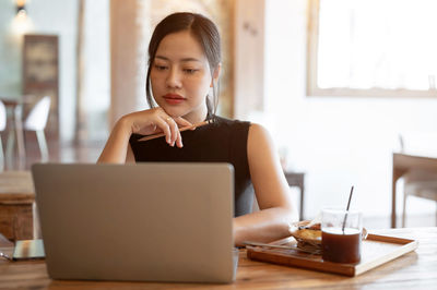 Portrait of woman using laptop while sitting on table