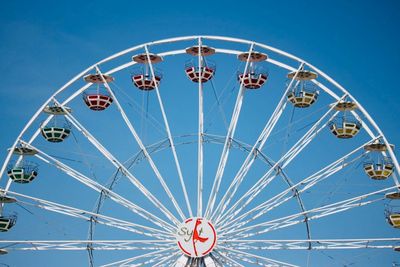 Low angle view of ferris wheel against blue sky