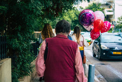 Rear view of people walking on street in city