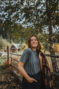 Portrait of a smiling young woman standing against trees