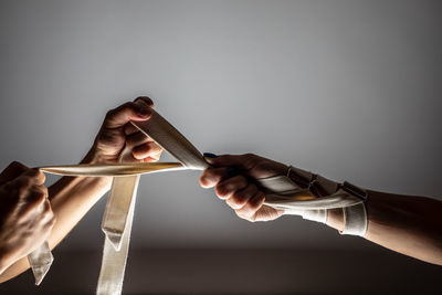 Close-up of people holding rope against wall