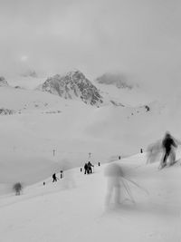 People skiing on snow covered mountain against sky