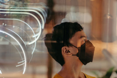 An in camera double exposure shot of a boy wearing a face mask in a mall at night