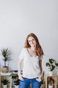 Happy young woman standing against wall