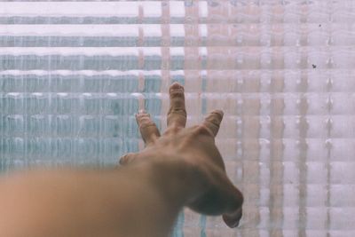 Cropped hand by glass window at home