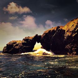 Rock formation by sea against sky