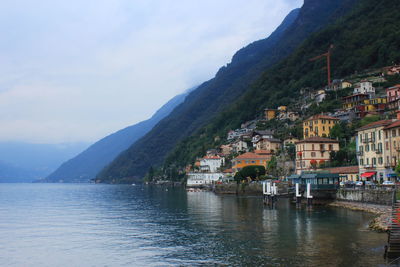 Town by lake and mountains against sky