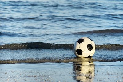 Soccer ball floating in the sea and hit the waves on the beach.