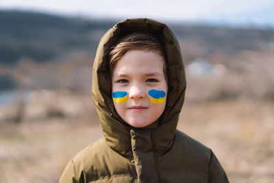 Portrait of a ukrainian boy with a face painted with the colors of the ukrainian flag.