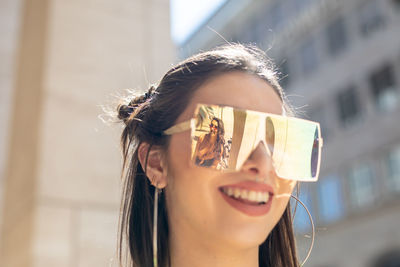 Young woman wearing sunglasses with reflection of friend