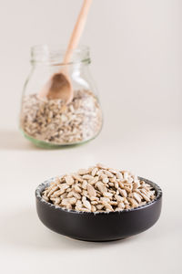 Peeled sunflower seeds in a bowl and in a glass jar on the table. organic food. vertical view