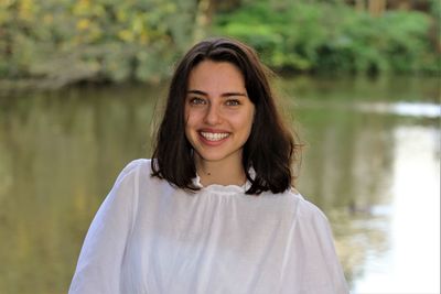 Portrait of smiling young woman standing against lake
