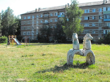 Sculpture on field by building against sky