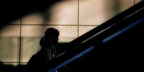 Side view of silhouette woman standing against window