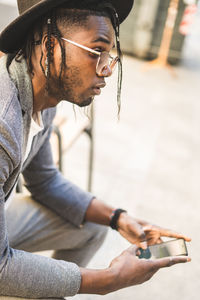 Midsection of man using mobile phone while sitting outdoors