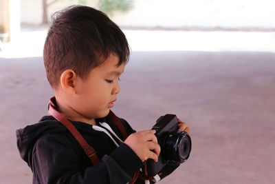 Close-up of boy holding camera while standing on road