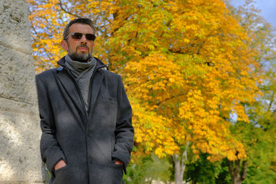 Portrait of man standing in autumn leaves