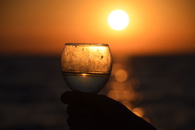 Close-up of beer glass against orange sunset sky