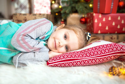 Portrait of cute girl lying down by christmas tree