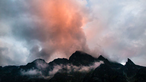 Low angle view of mountains against cloudy sky at sunset