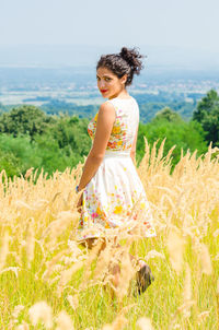 Young woman standing on field against sky