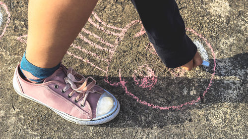 Low section of woman drawing on concrete