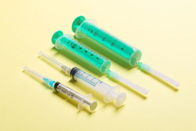 Close-up of syringe on yellow background