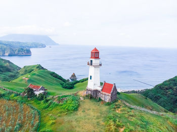 Lighthouse amidst sea and buildings against sky