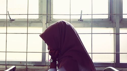 Woman in hijab sitting by window