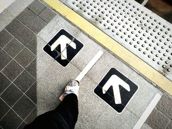 Low section of woman standing by sign on footpath