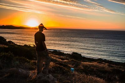 Silhouette man standing at beach during sunset