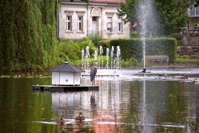 Fountain by lake against building