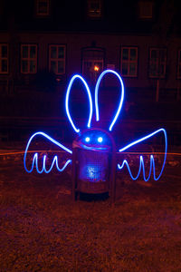 Light painting on garbage bin against house at night