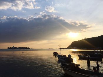 Boats moored on sea against sky during sunset