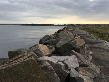 Scenic view of stones next to sea against cloudy sky