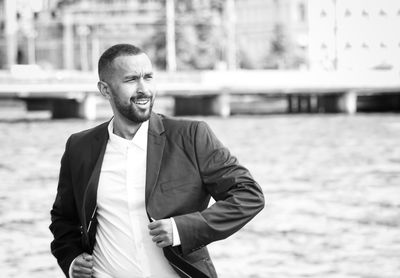 Man in blazer looking away while walking outdoors