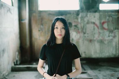 Portrait of young woman standing against wall