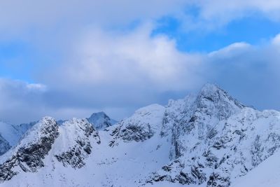 Low angle view of snow mountains against blue sky